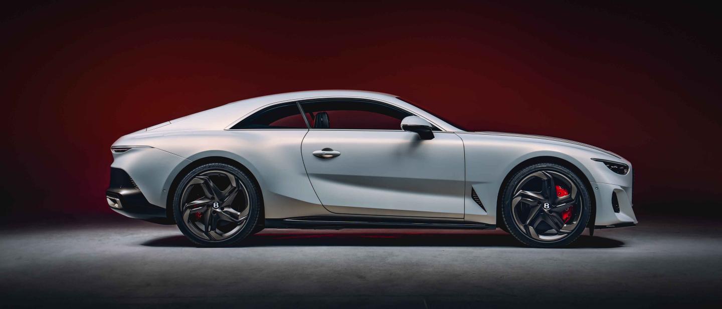 Side view of Bentley Batur featuring 22 inch black polished directional alloy wheels and Bentley branded red brake calliper, with lower wing vent in view.