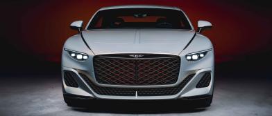 Bentley Batur front view featuring diamond patterned gloss black grille with orange accents and sharp eagle eye shaped headlights with flying wings bentley badge on leading end.