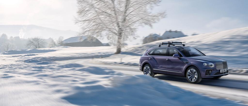 Side view of Bentley EWB Azure in Tanzanite Purple colour, featuring overhead ski and snowboard carrier, effortlessly driving along icy road.