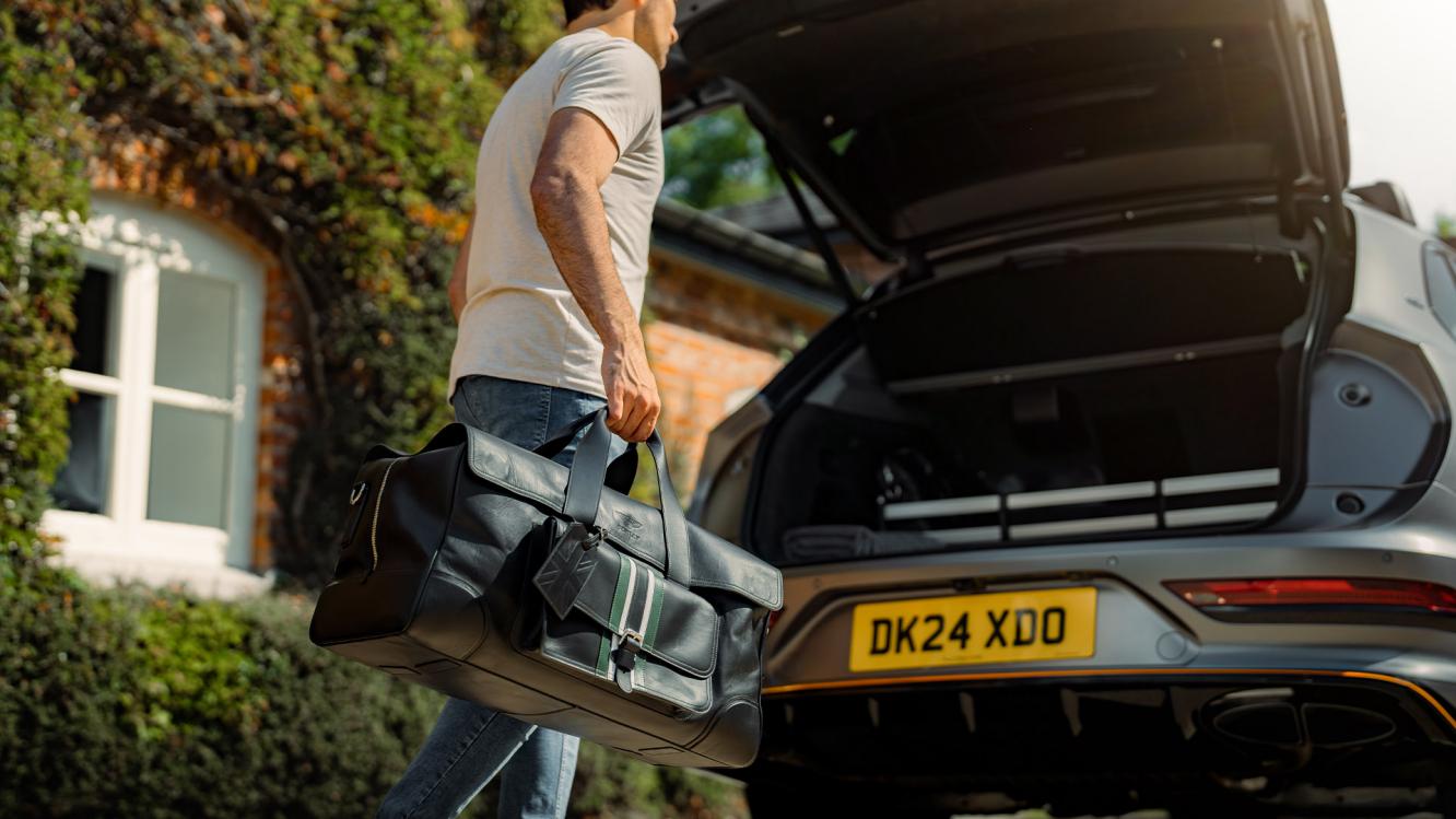A model placing the Bentley fitted luggage set in Belluga Hide with Tourmaline Green accents in the back of a Bentayga S Black Edition in Anthracite Exterior Colour