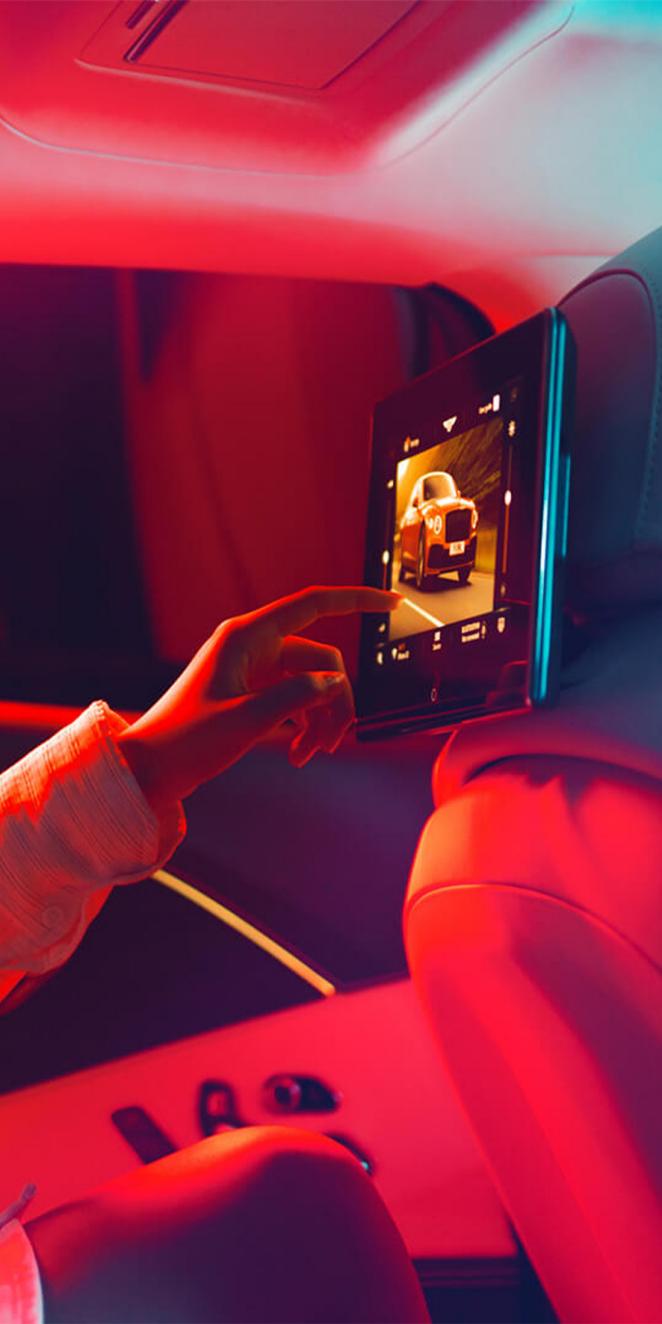 Passenger interacting with Bentley's 10.1 inch Rear Entertainment System screen.