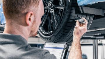 A Bentley technician checking tread depth of Bentley seasonal tires.