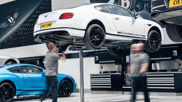 Bentley technician working underneath a Bentley Continental GT, raised on hydraulic car jack.