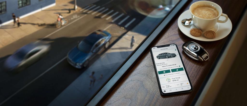 Smartphone featuring My Bentley App and Bentley Key fob in view with a cup of coffee