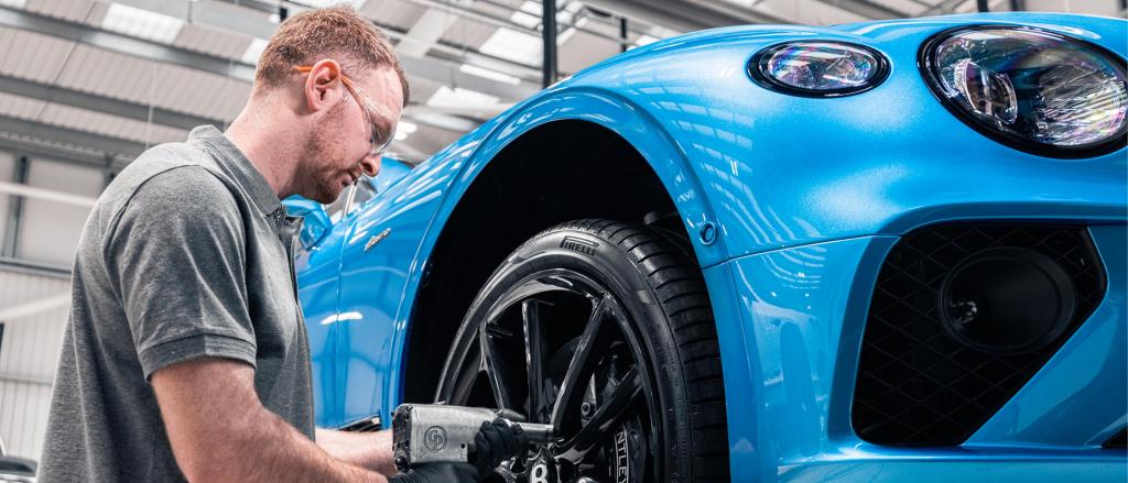Bentley technician tightening front right wheel nuts of Bentley Continental GT Azure in Kingfisher By Mulliner colour 