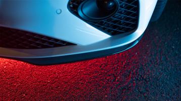 Close up of front left bumper of Continental GT with sensor and red underlight in view