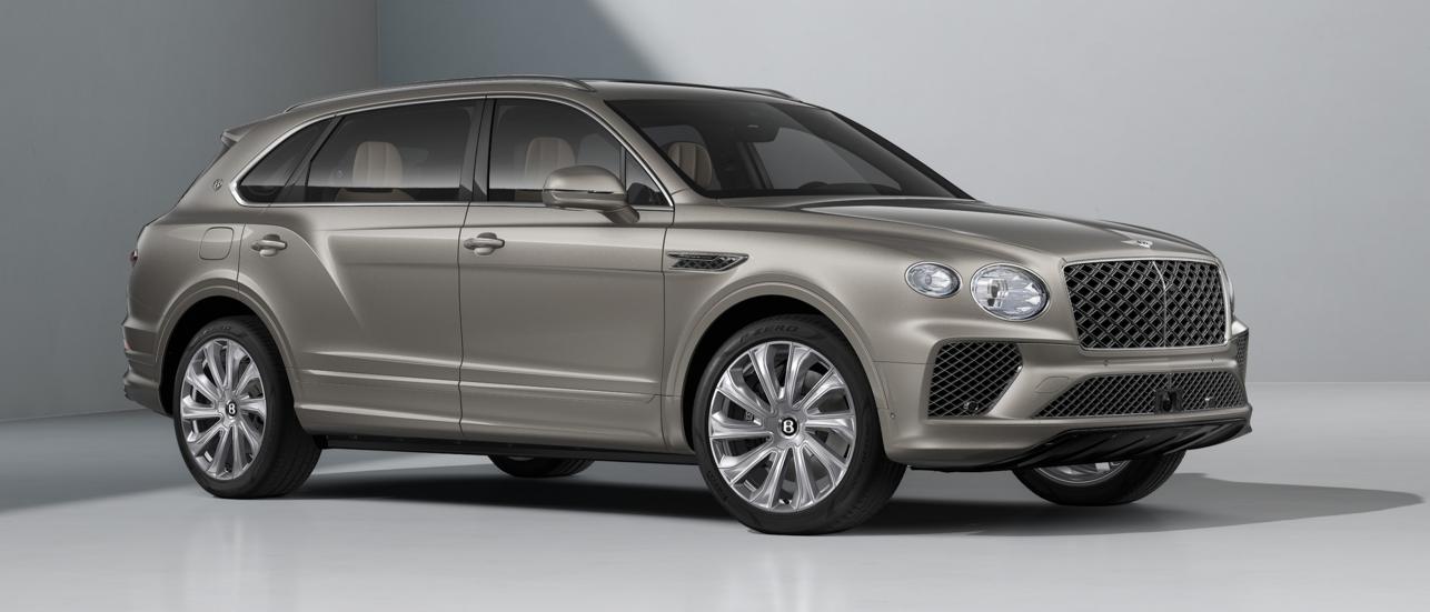 Bentley Bentayga EWB Mulliner side view in Tanzanite Purple parked in doors featuring 22" inch Mulliner Wheel  - Polished, with a man standing in view