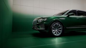 Wisdom Kaye standing next to the front three quarter of the Bentayga Atelier Edition in an Emerald exterior colours with bright chrome accents