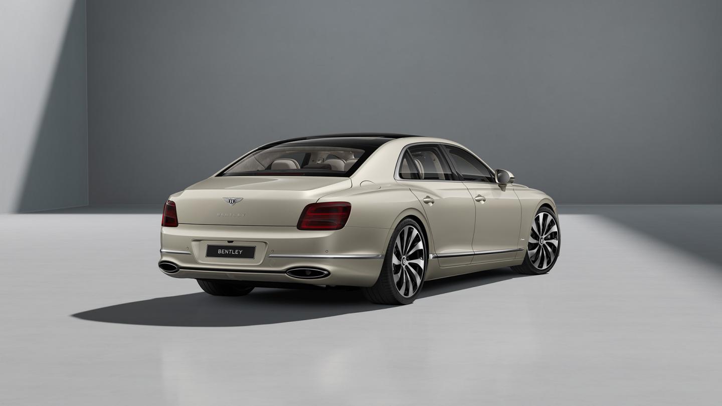 Rear three-quarter shot of the Bentley Flying Spur Azure in White Sand with Bright Chrome Exterior detailing.