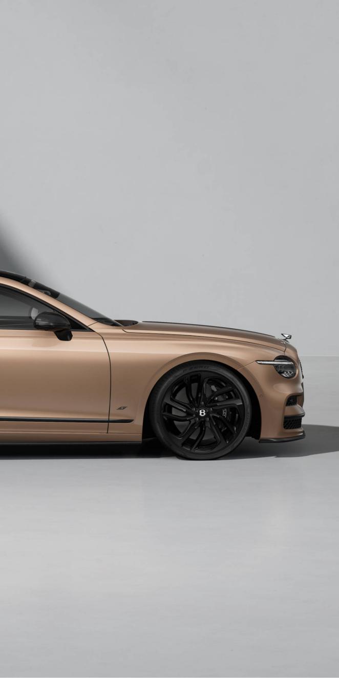 Front side view of the Bentley Flying Spur S in Rose Gold with Blackline Specification and dark exterior detailing.